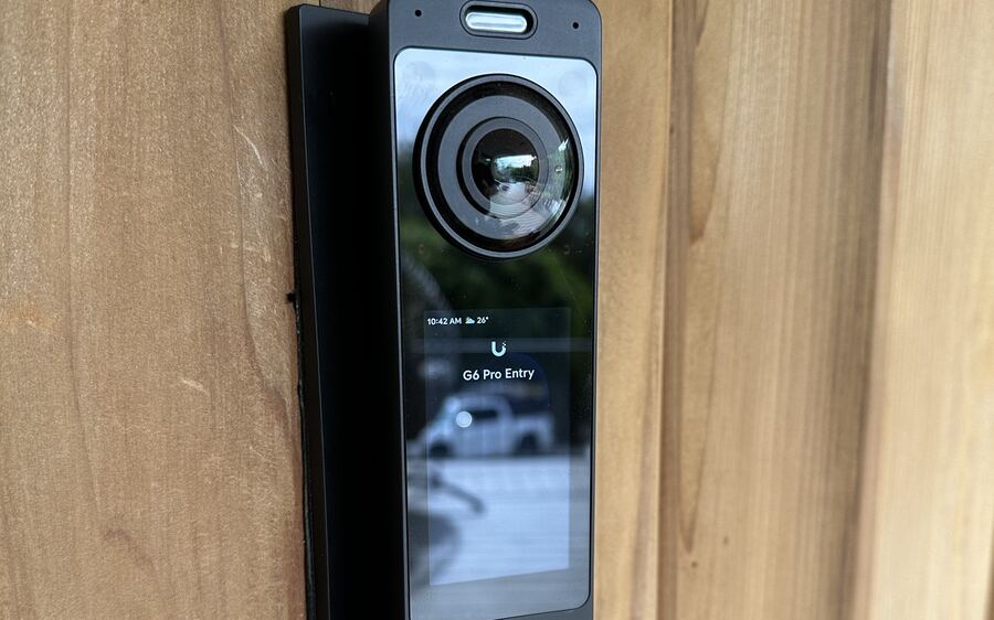 UniFi video doorbell with camera and display mounted on a wood-clad entry